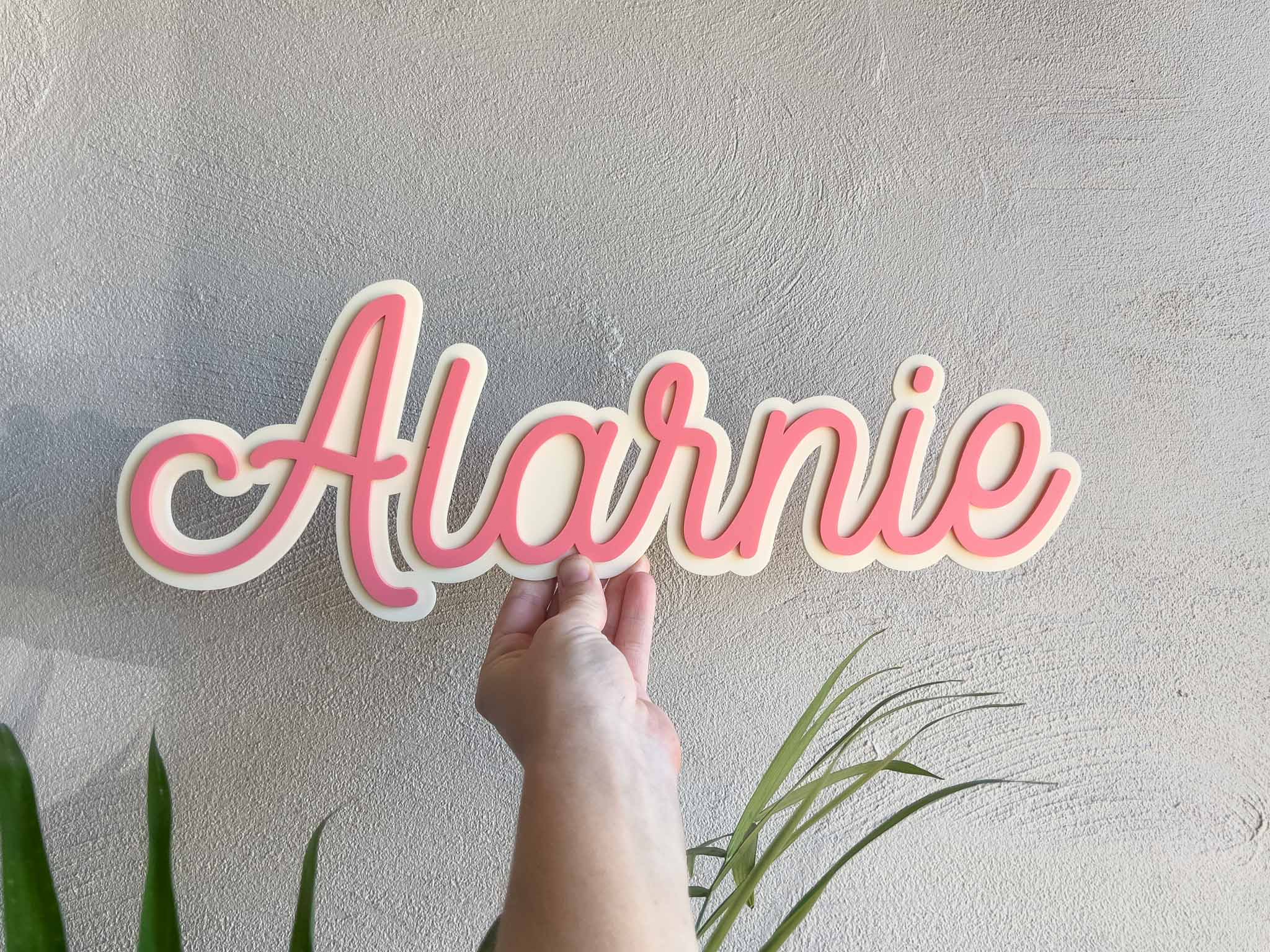 Cute beige and salmon pink colour 3D acrylic name plaque that says 'Alarnie'.