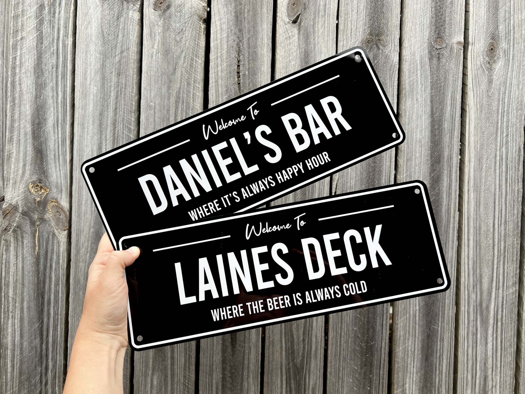 Two personalised metal signs held against a wooden background