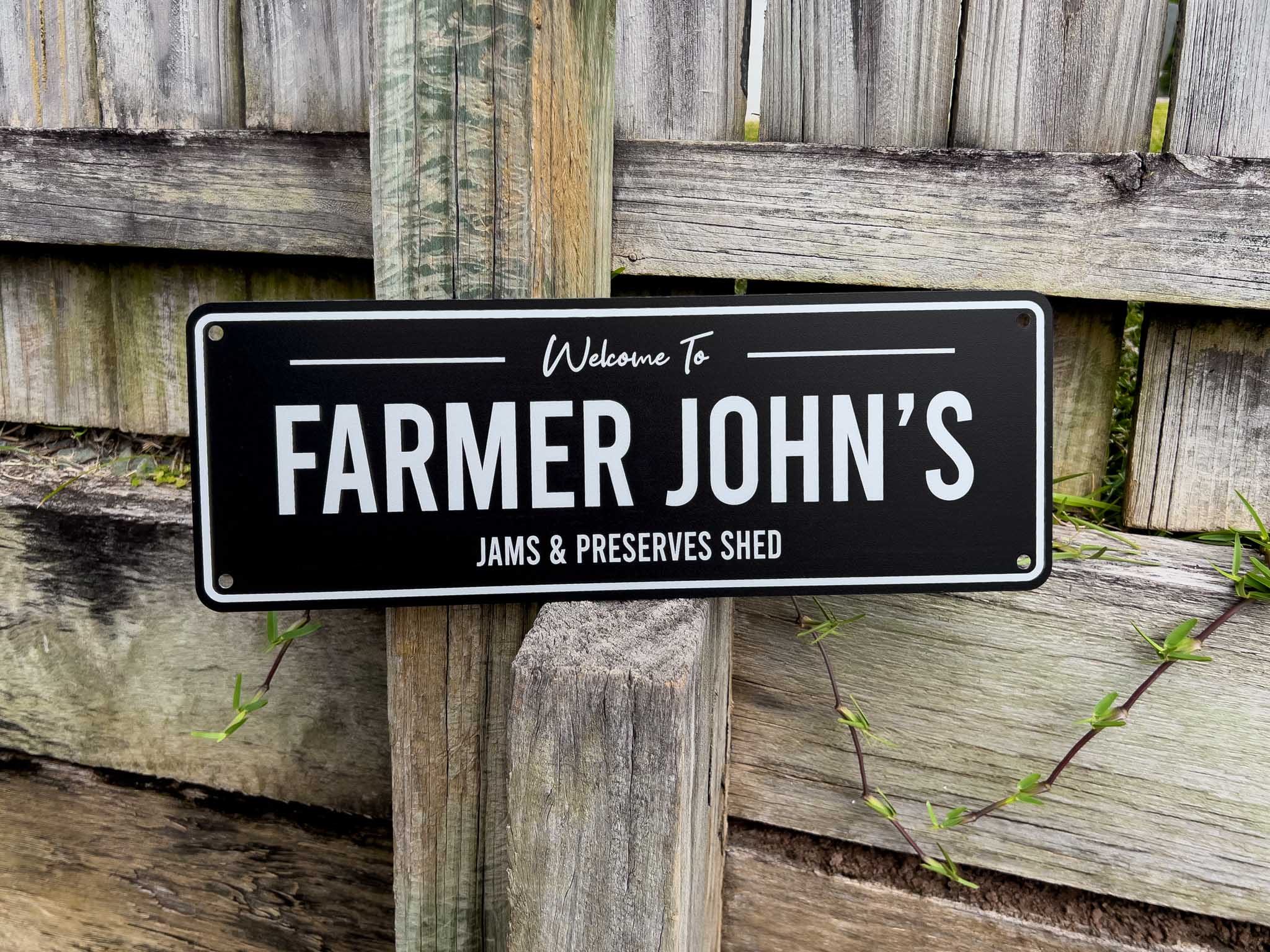 Custom printed black and white metal sign that reads 'Farmer John's Jams & Preserves Shed'.