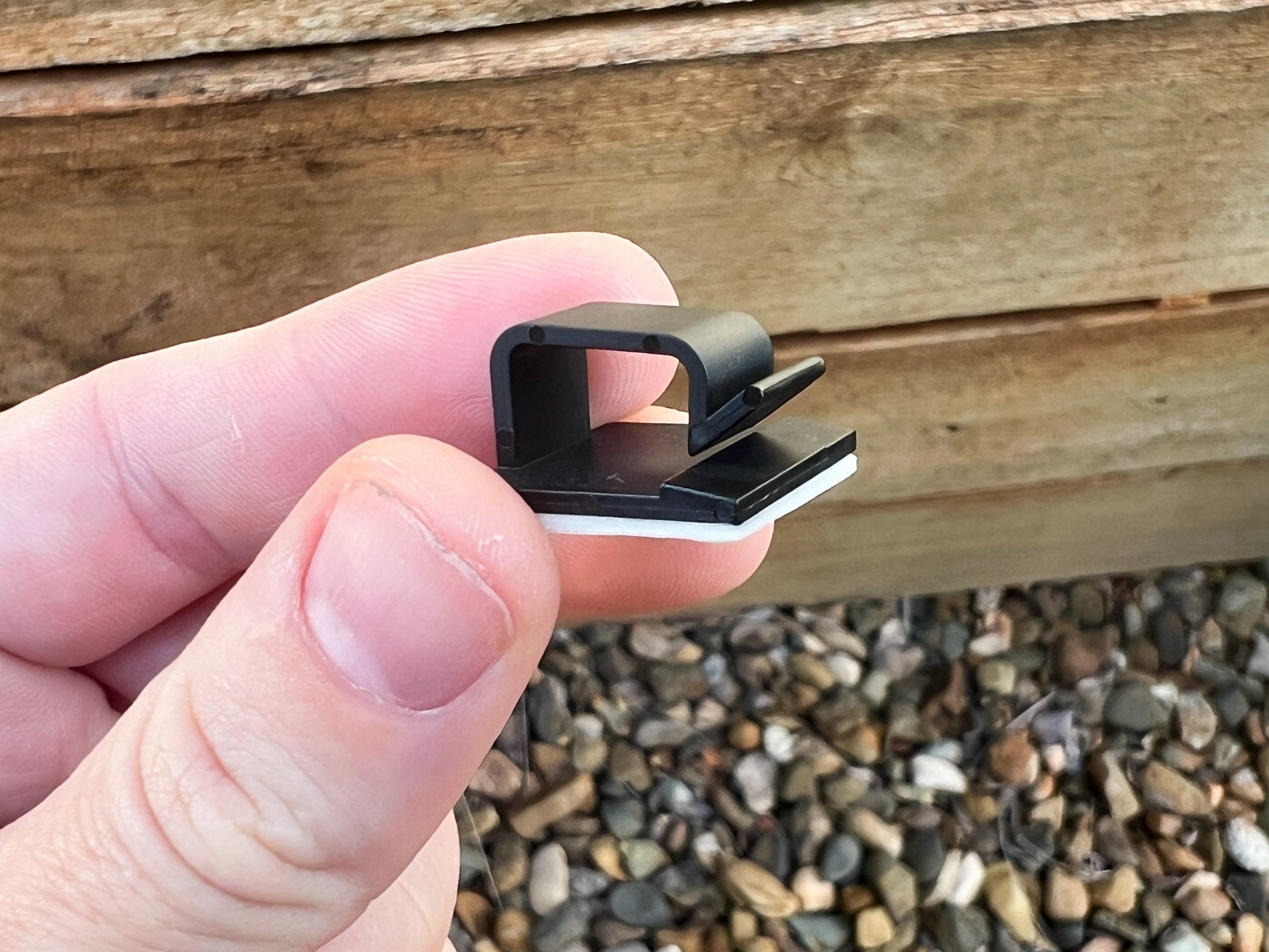 Handing hold a close up side view of a black plastic mounting clip