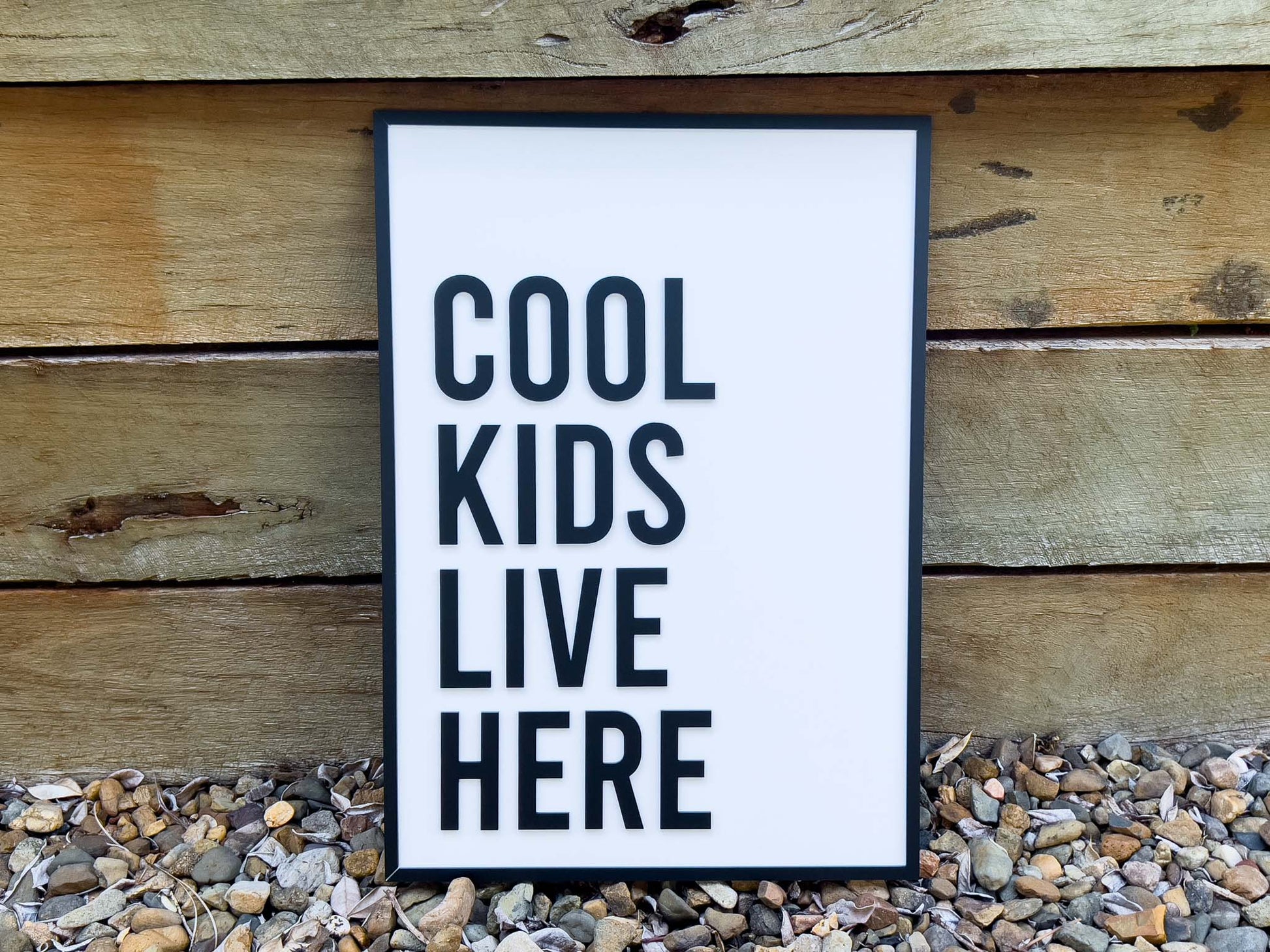 Framed 3D acrylic sign with 'Cool Kids Live Here' text on a wooden background