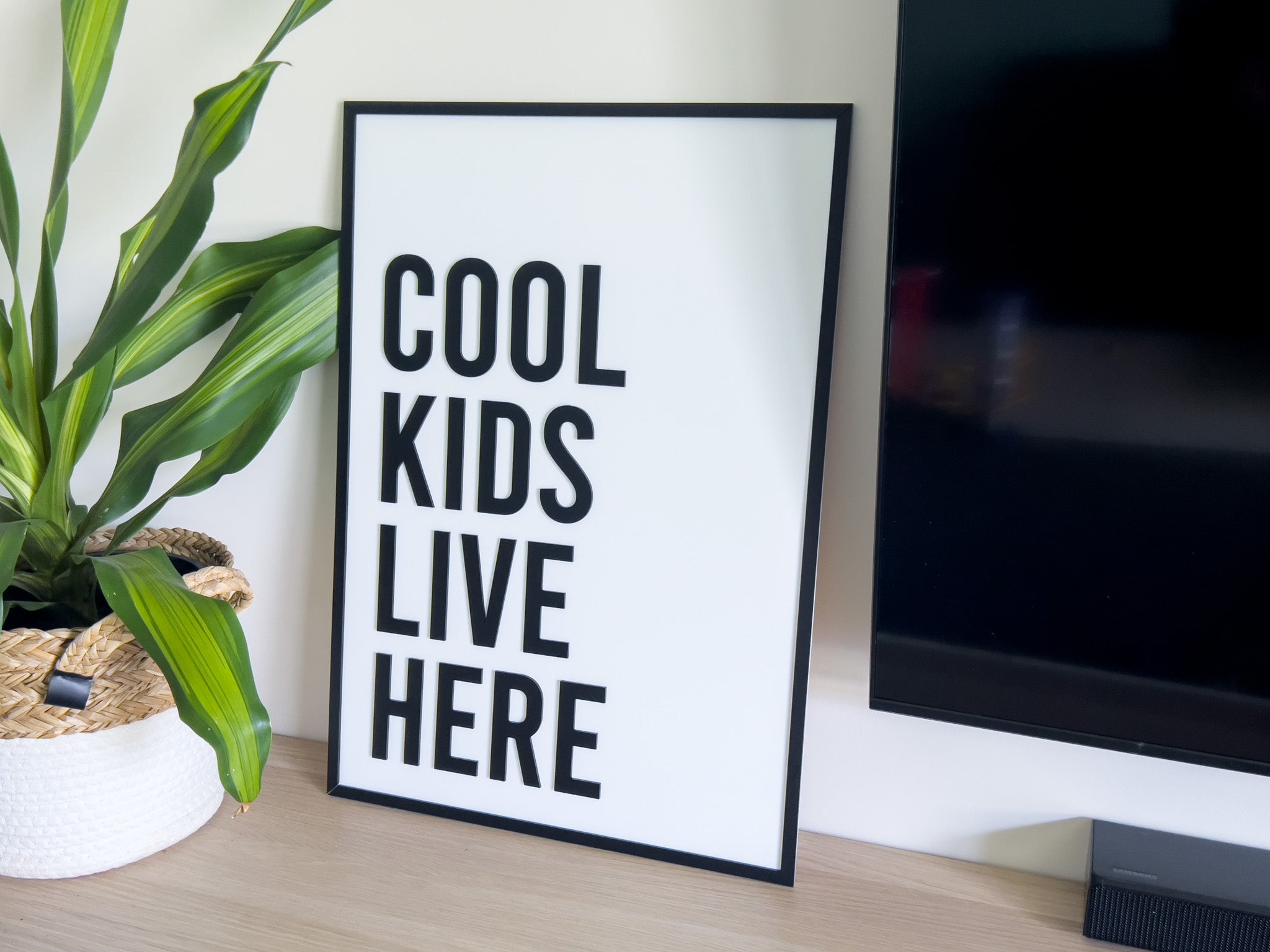 3D acrylic custom text plaque that reads 'COOL KIDS LIVE HERE' sitting on a timber desk | Coji Designs