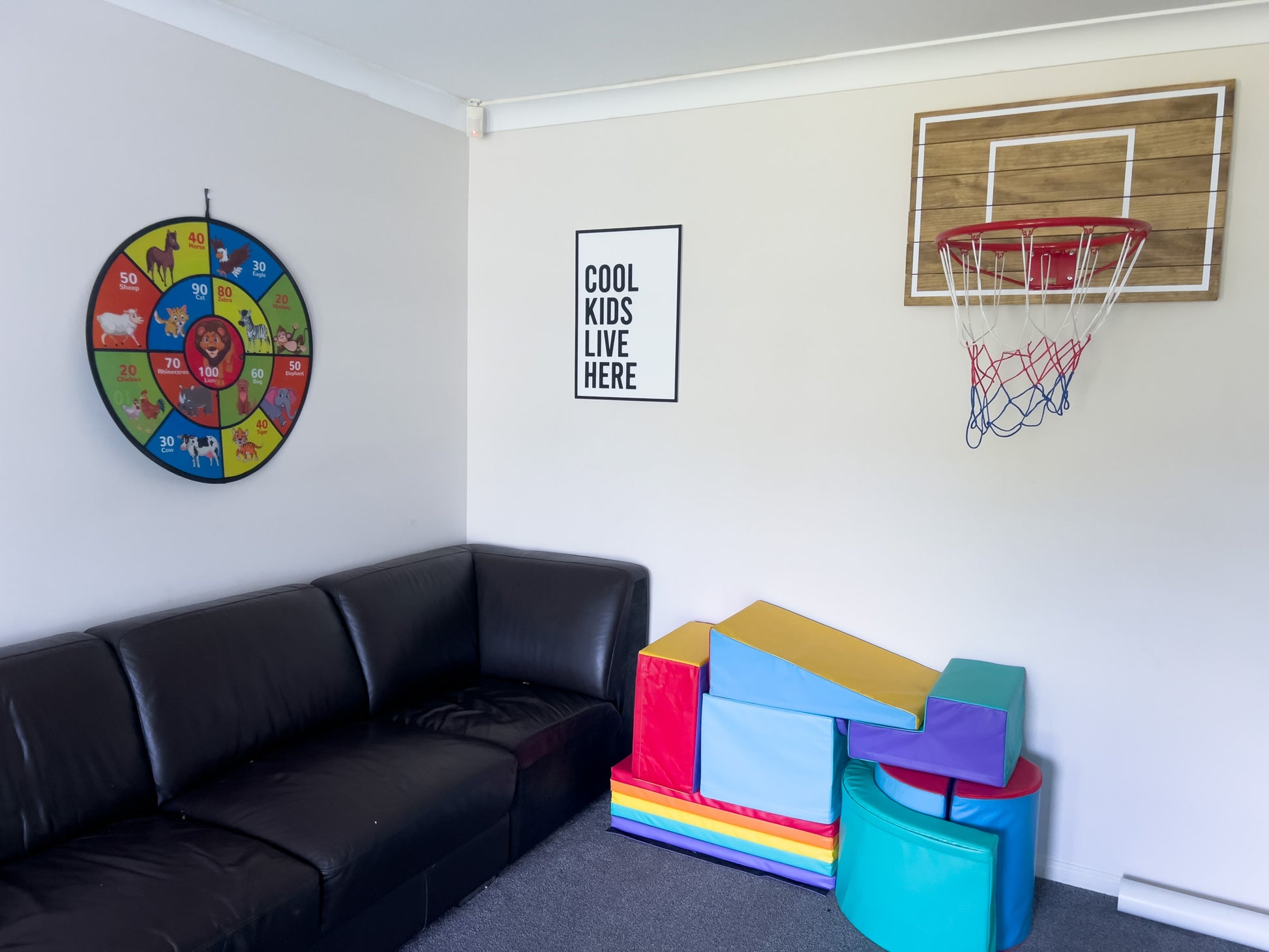 Custom black and white 3D quote sign hanging in a kids playroom. The sign says 'COOL KIDS LIVE HERE'.