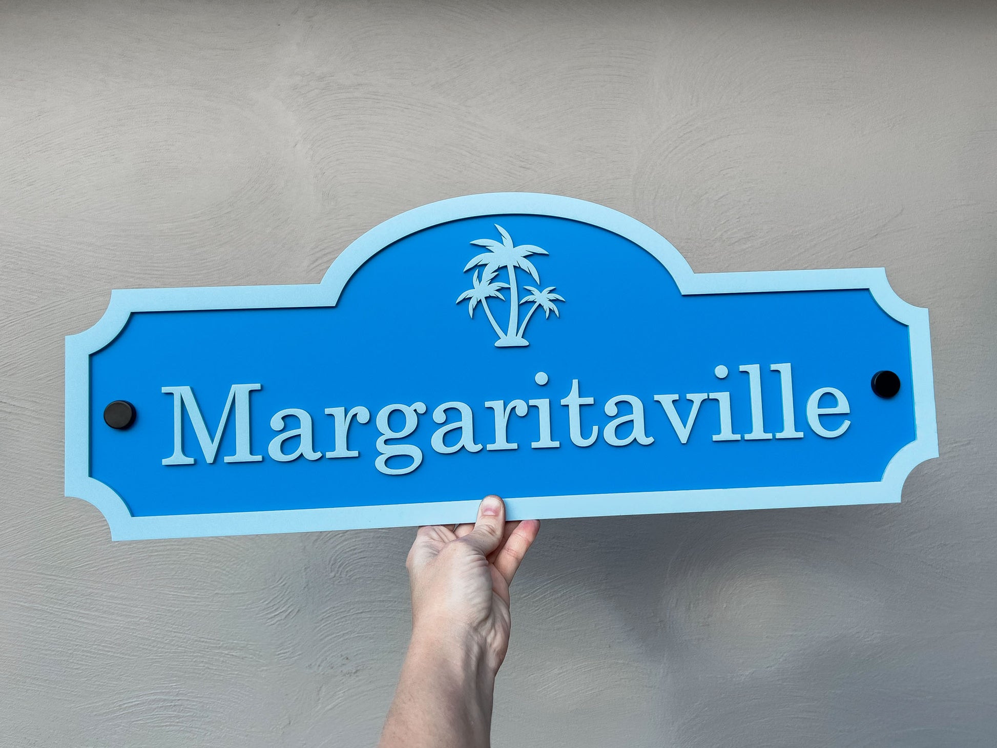 Blue 'Margaritaville' sign held against a gray background