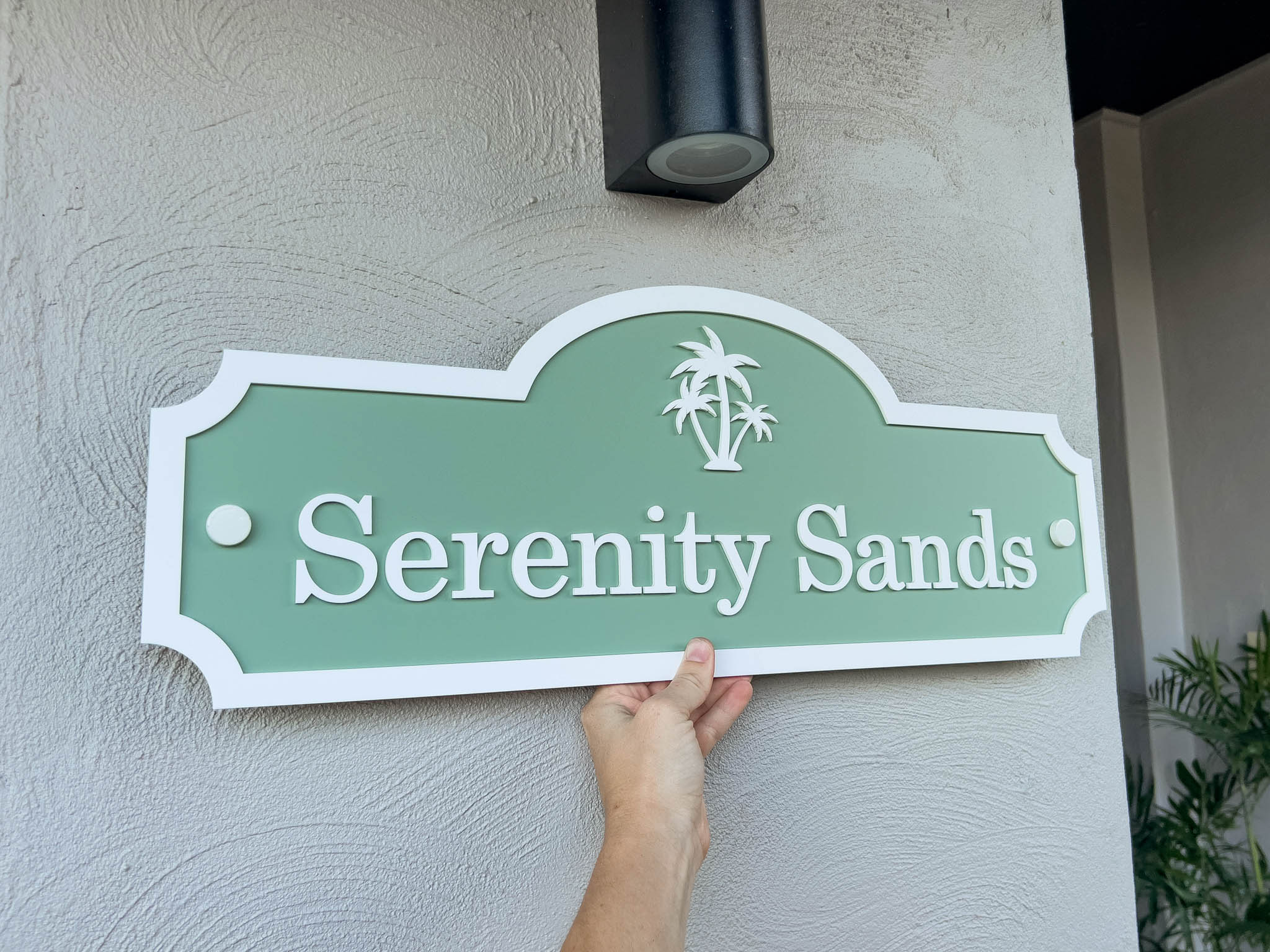 Green and white custom palm tree sign with the text 'Serenity Sands'.