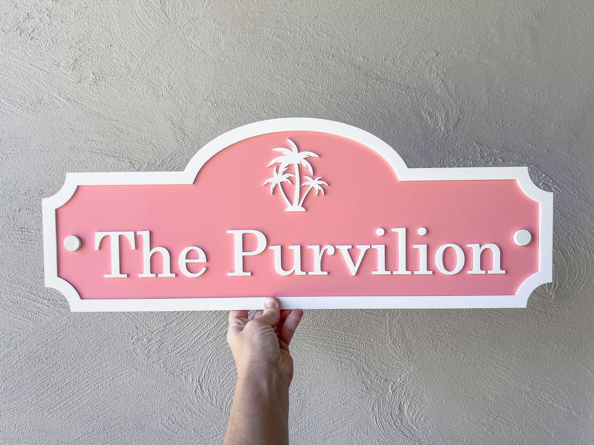 Pink sign with 'The Purvilion' text held against a gray wall