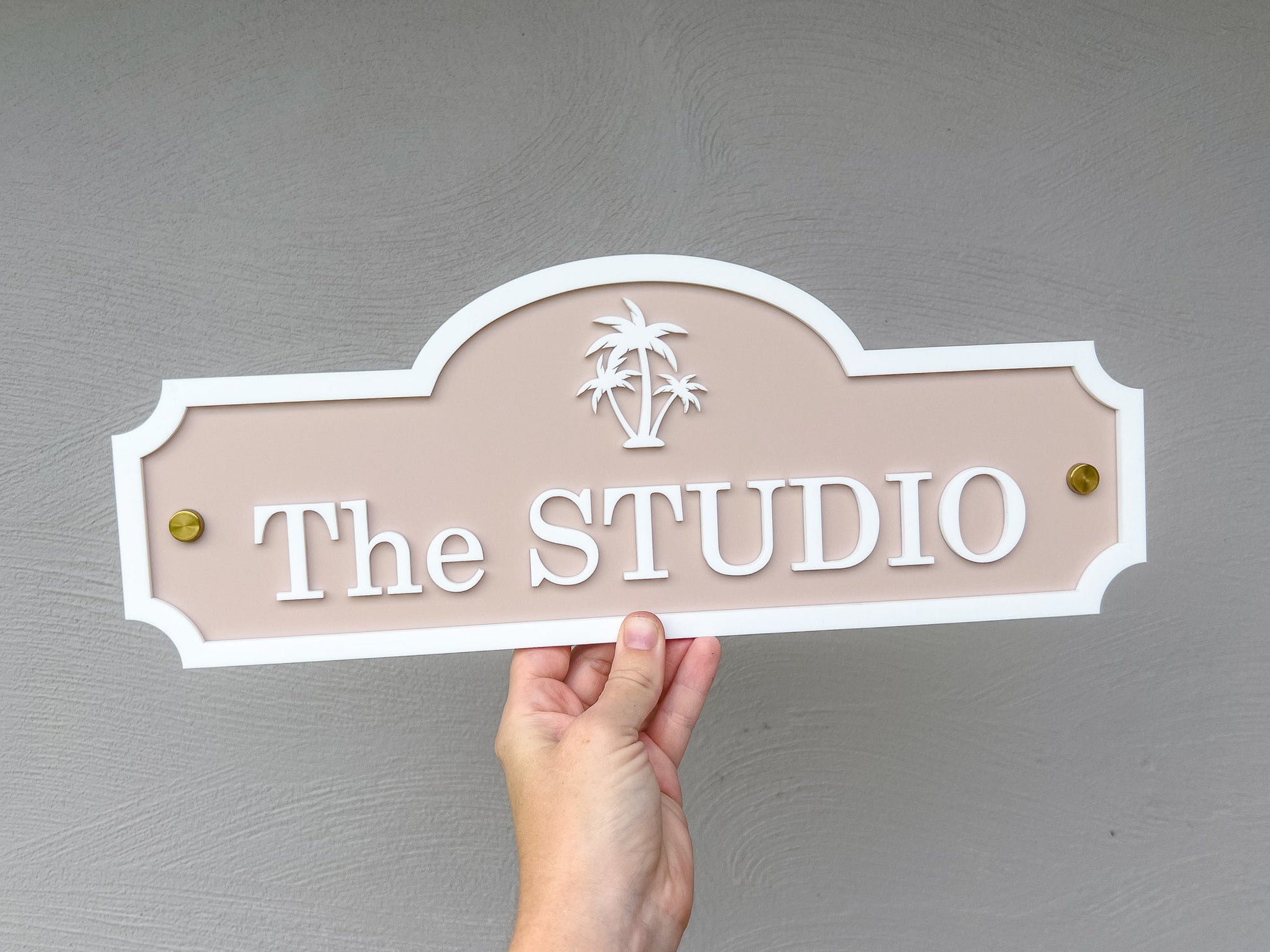 Beige and white custom coastal sign with gold mounts with the text 'The STUDIO'.