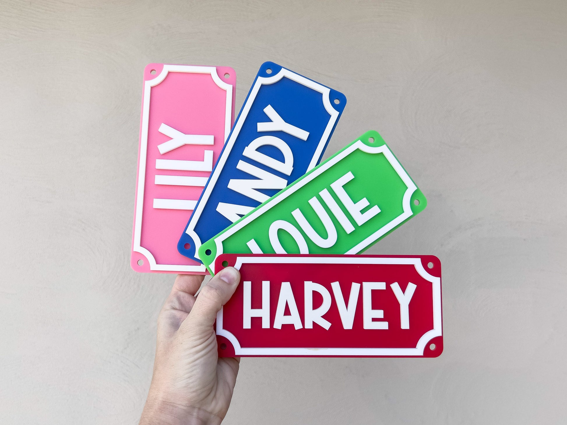 Four colorful name plates held by a hand against a plain background