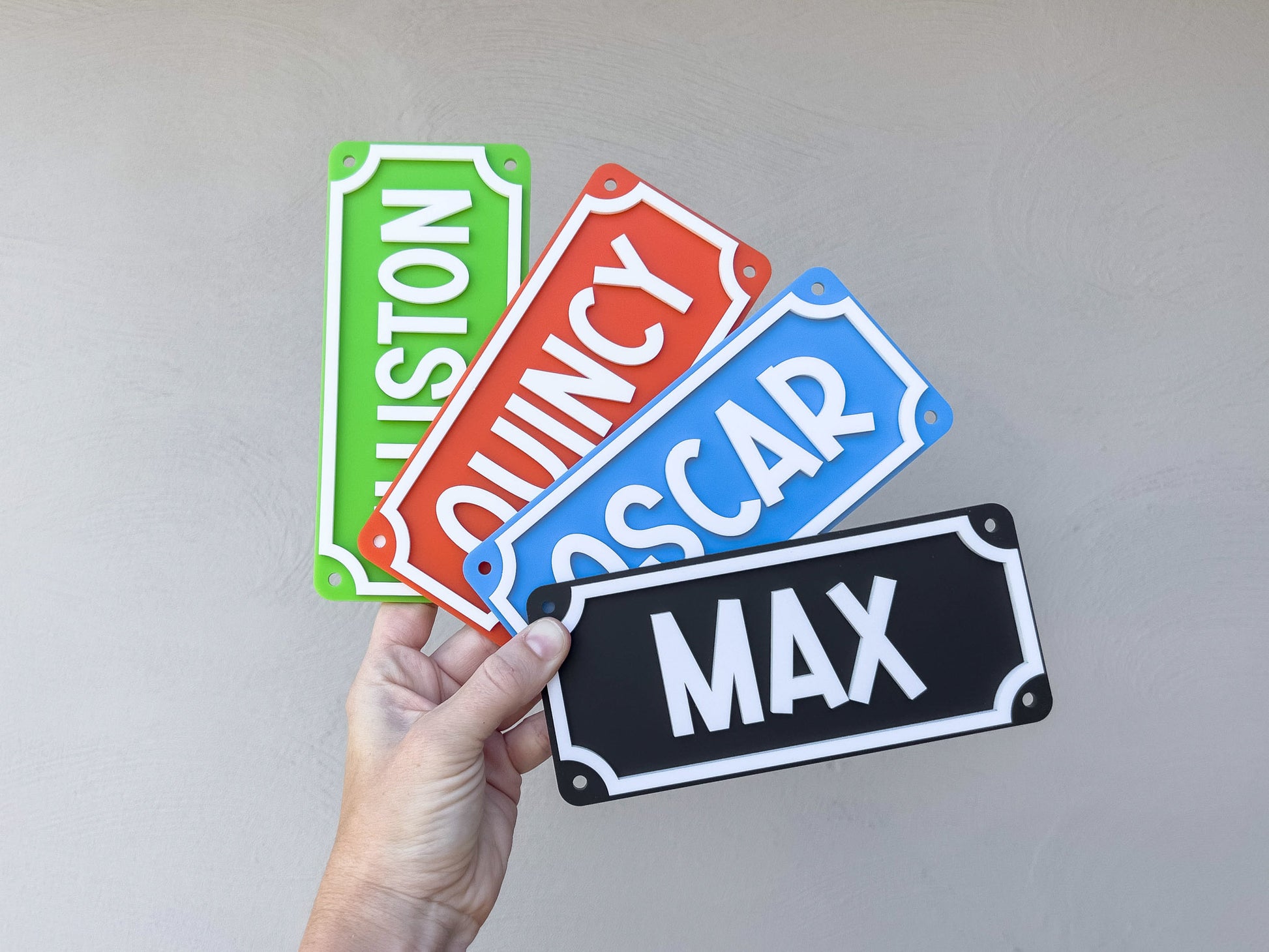 Four colorful name plates held by a hand against a plain background