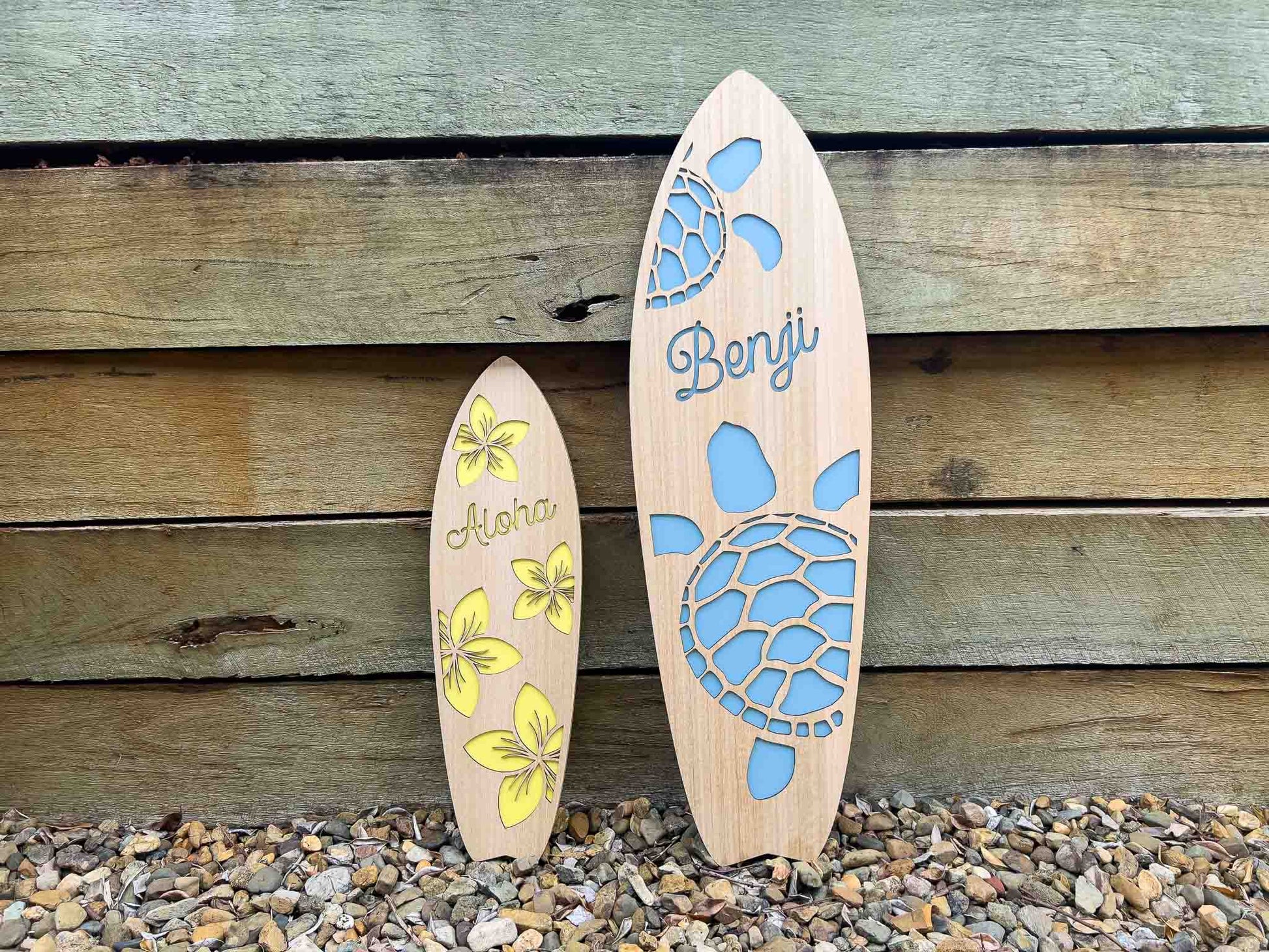 Two wooden surfboard-shaped signs with turtle designs and text against a wooden background.
