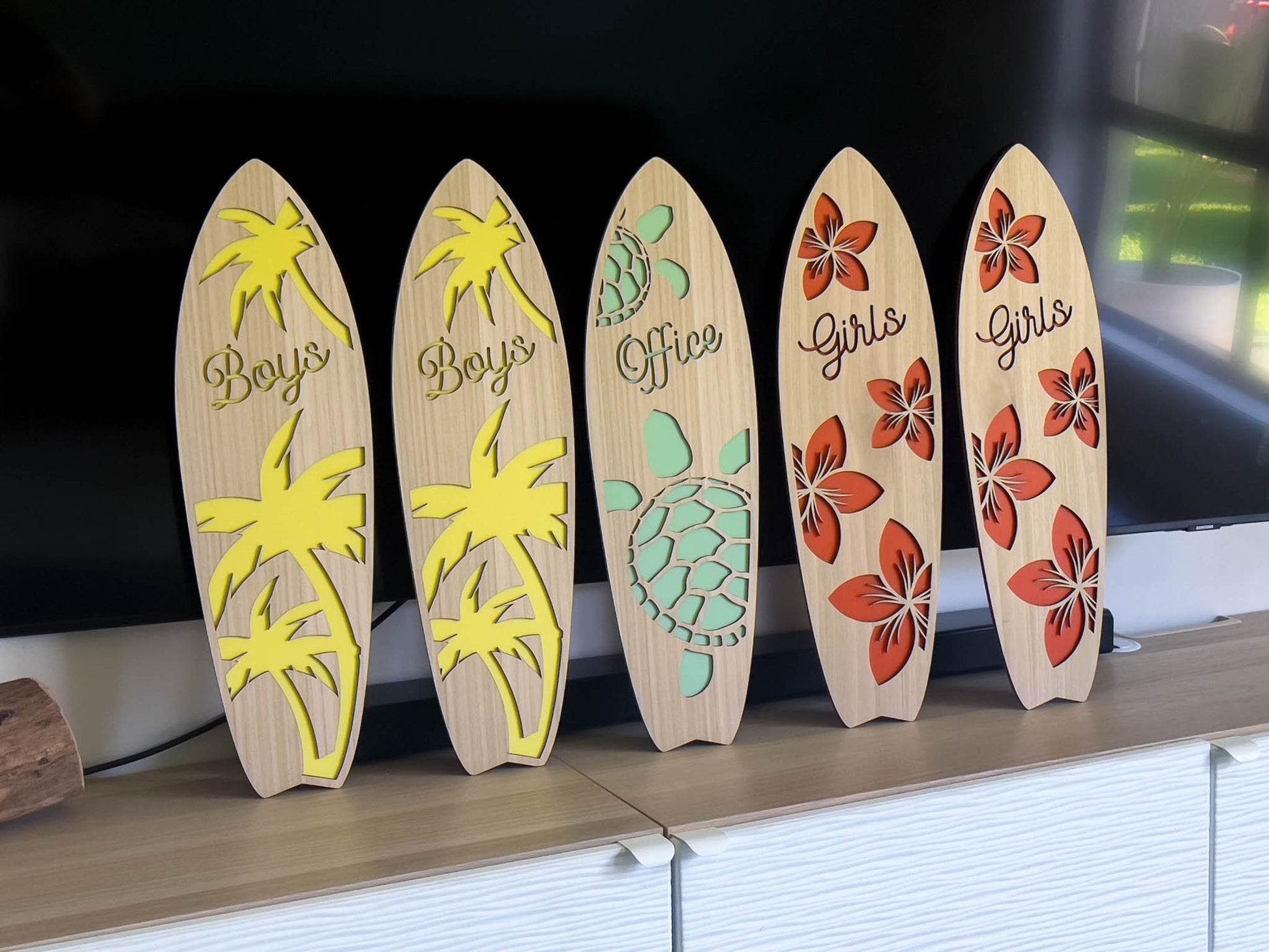 Set of decorative wooden surfboards with various designs on a shelf.