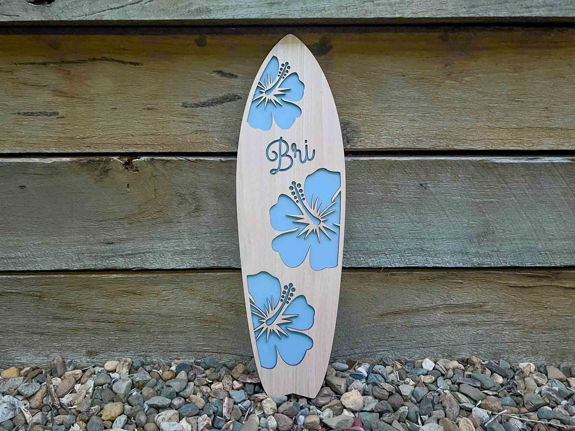 Custom handmade timber surfboard name plaque with 'Bri' and a coastal dusty blue background.