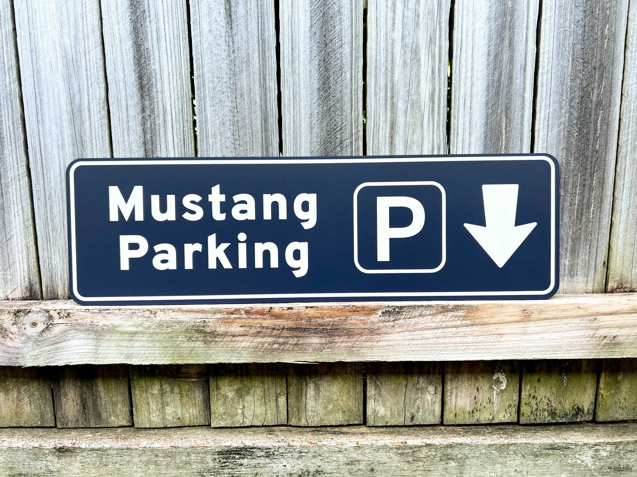 Mustang Parking sign with a white arrow pointing down on a wooden background