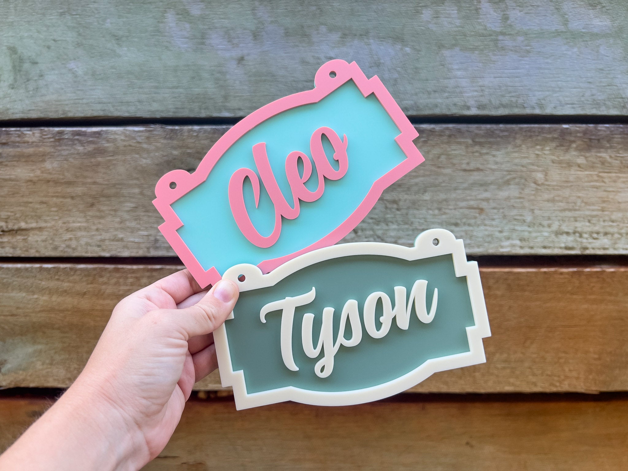 Two name tags, one pink and one white, held against a wooden background | Coji Designs