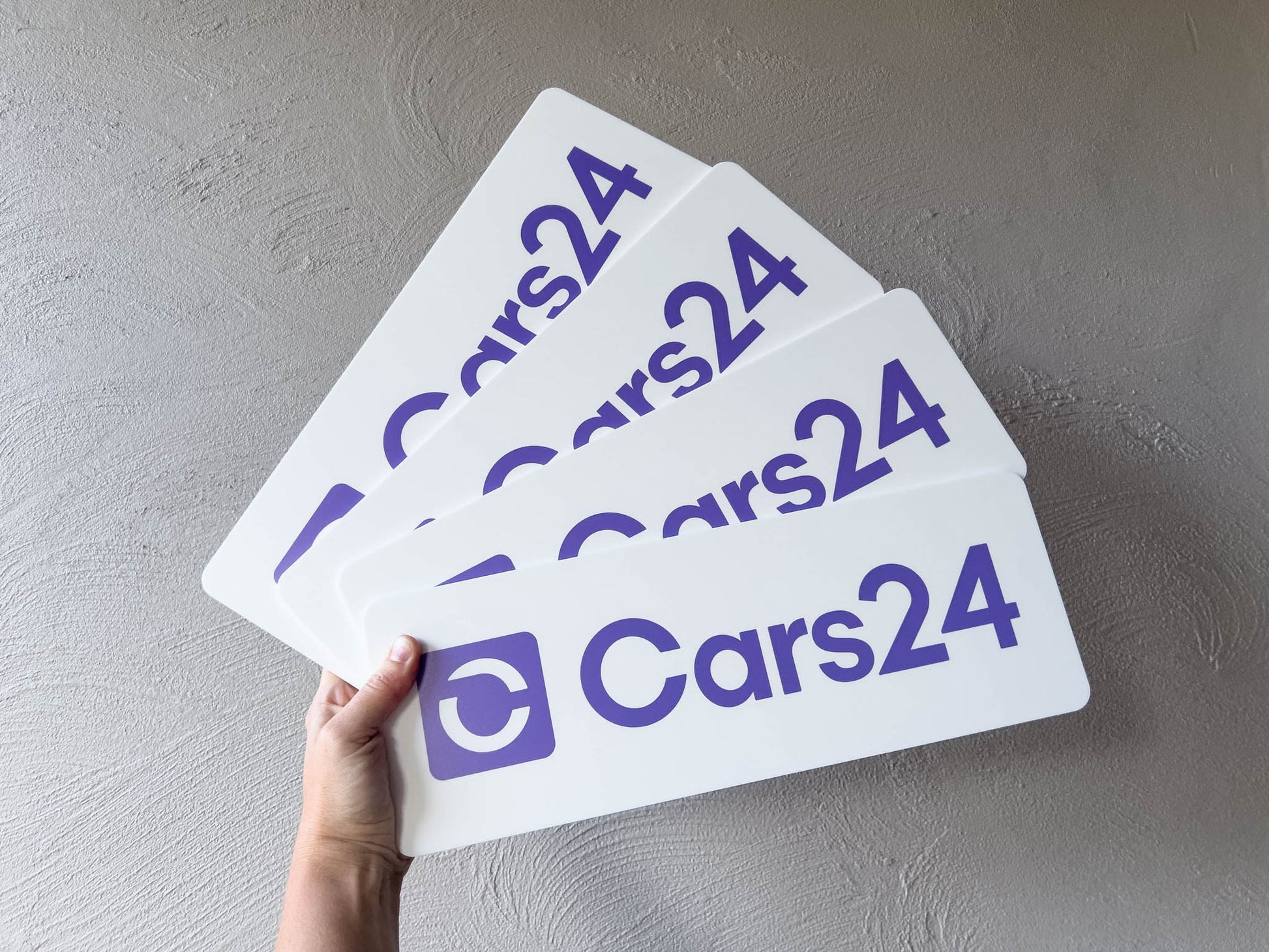 Hand holding custom printed white and purple logo plates
