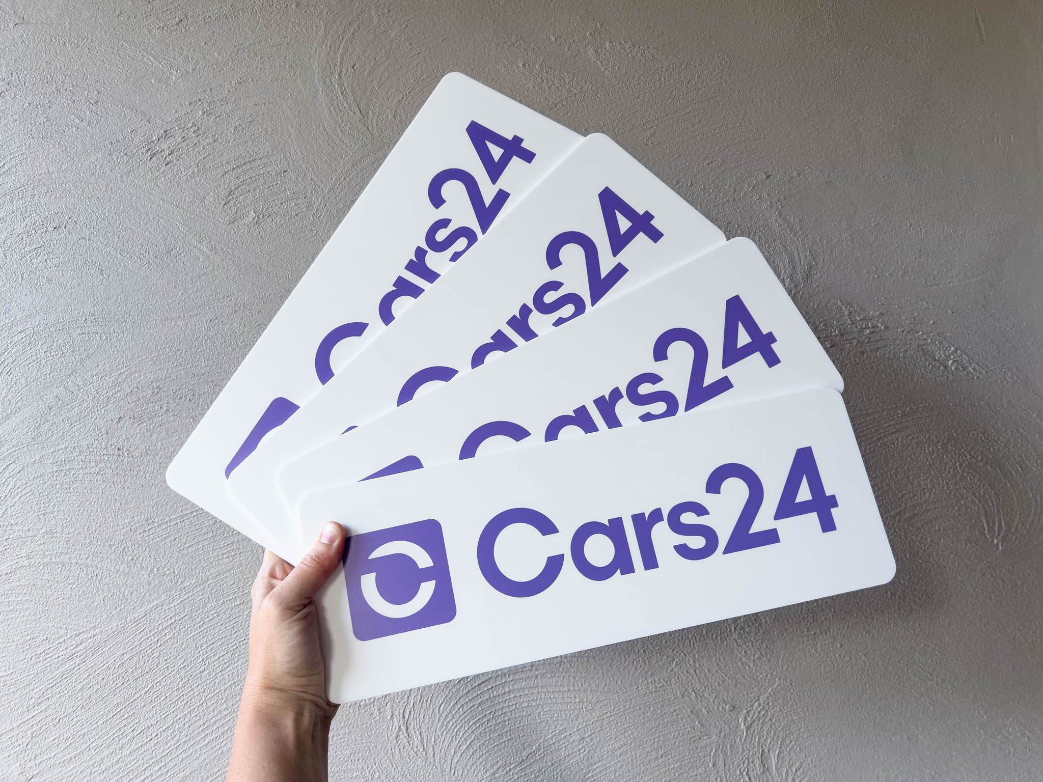 Hand holding custom printed white and purple logo plates