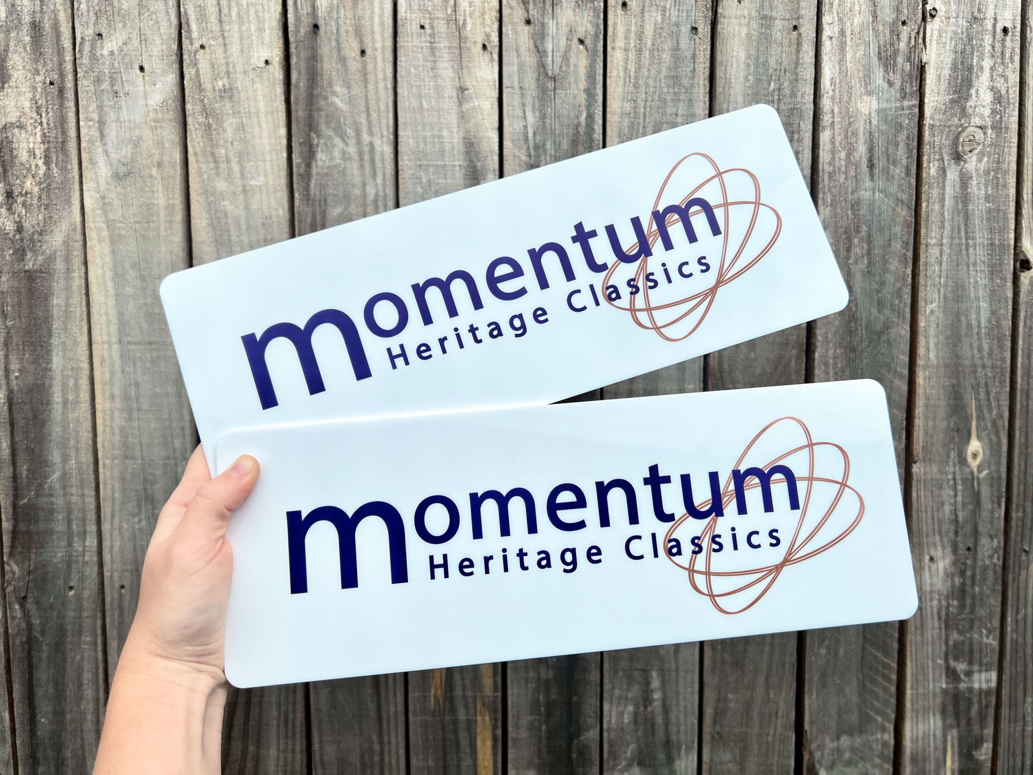 Two 'momentum Heritage Classics' white acrylic plates held against a wooden background