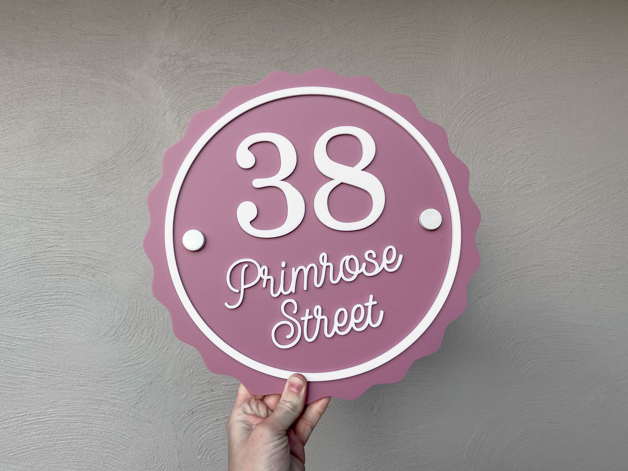 Round scalloped edge contemporary custom made street address sign in a rose pink and white colour that says '38 Primrose street'.