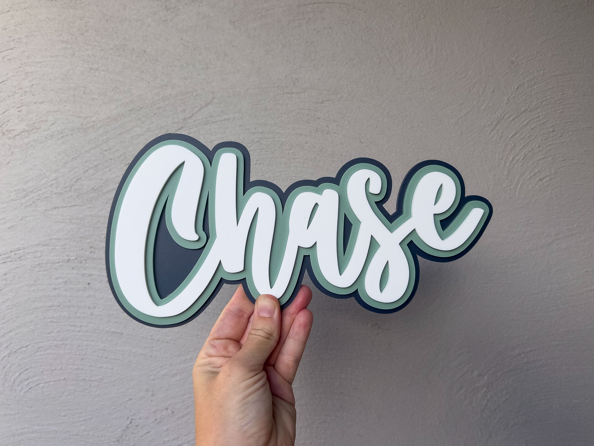 Surf style custom handmade 3D acrylic name sign with the name 'Chase' layered in dark blue, green and white.