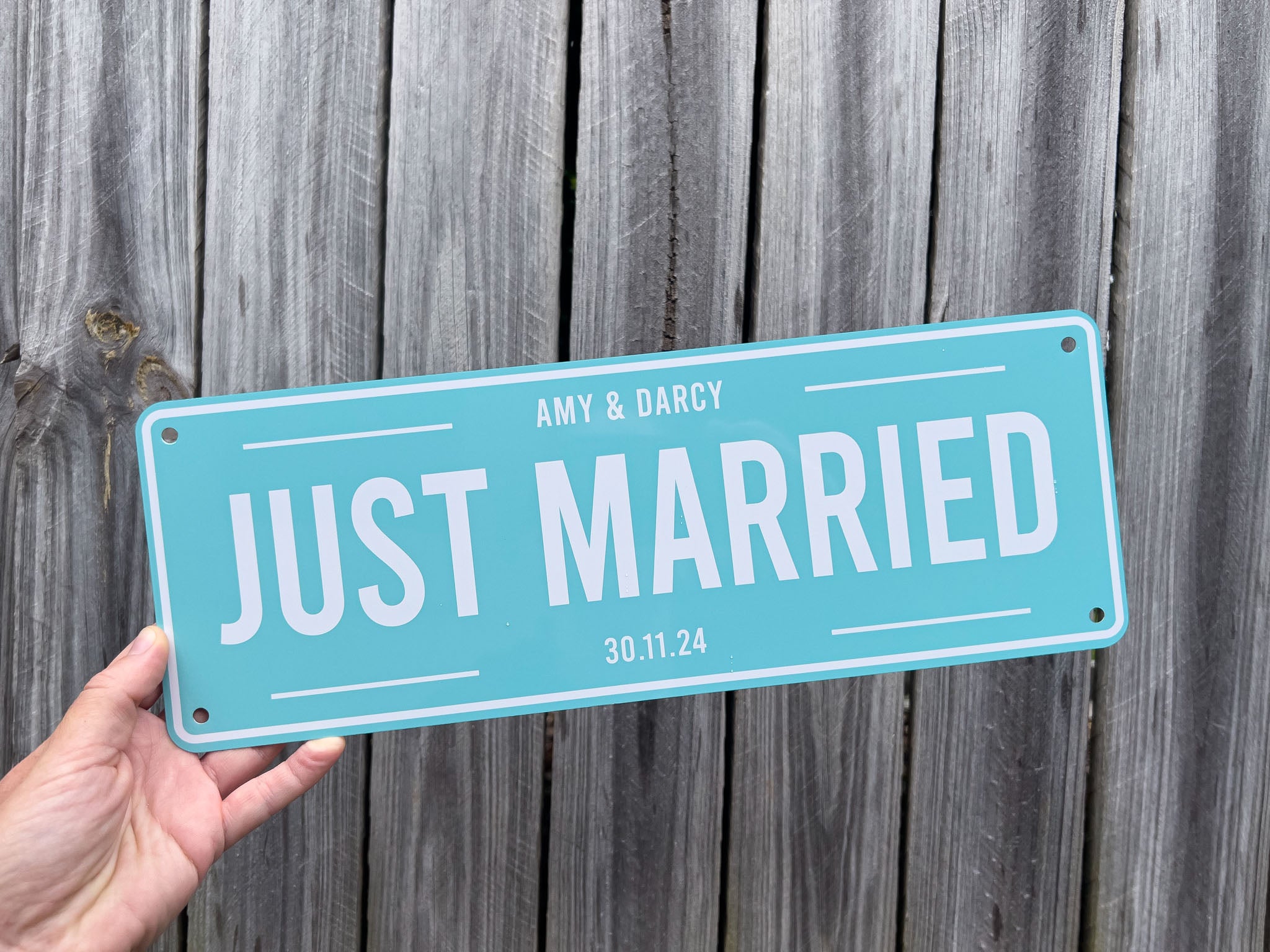 Hand holding a 'Just Married' Wedding plate with personalized names and date against a wooden background | Coji Designs