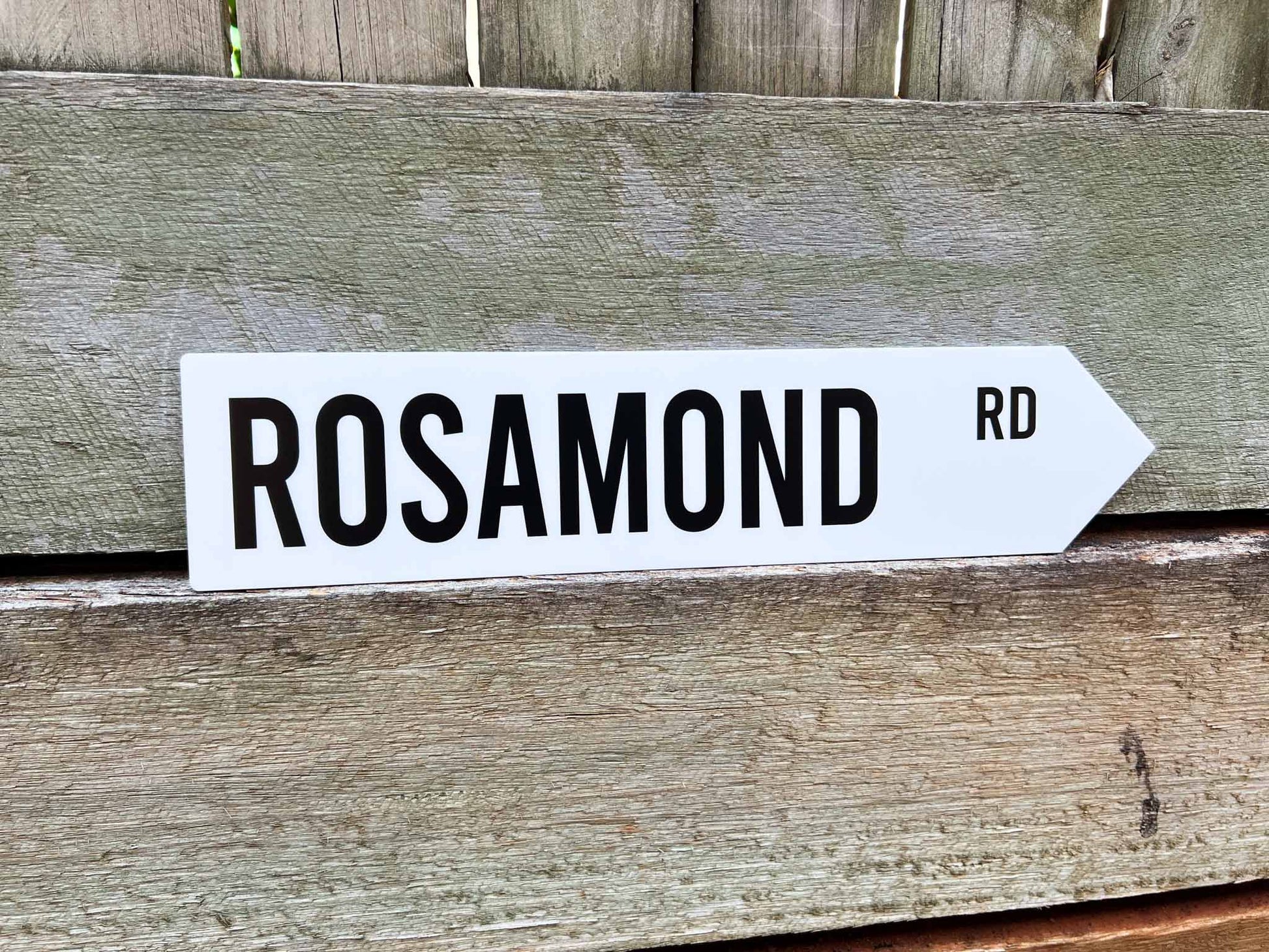 Classic white and black direction street sign pointing to the right that reads 'Rosamond Rd'.
