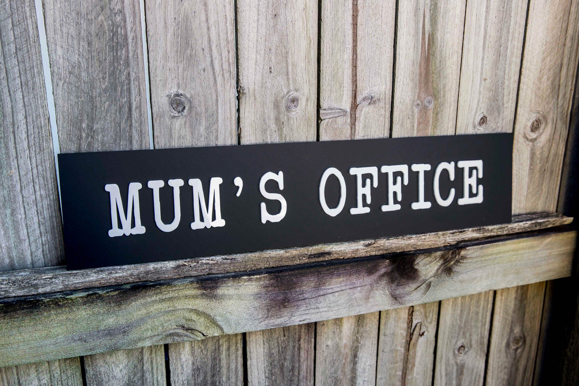 Wooden sign with 'MUM'S OFFICE' text on a wooden background