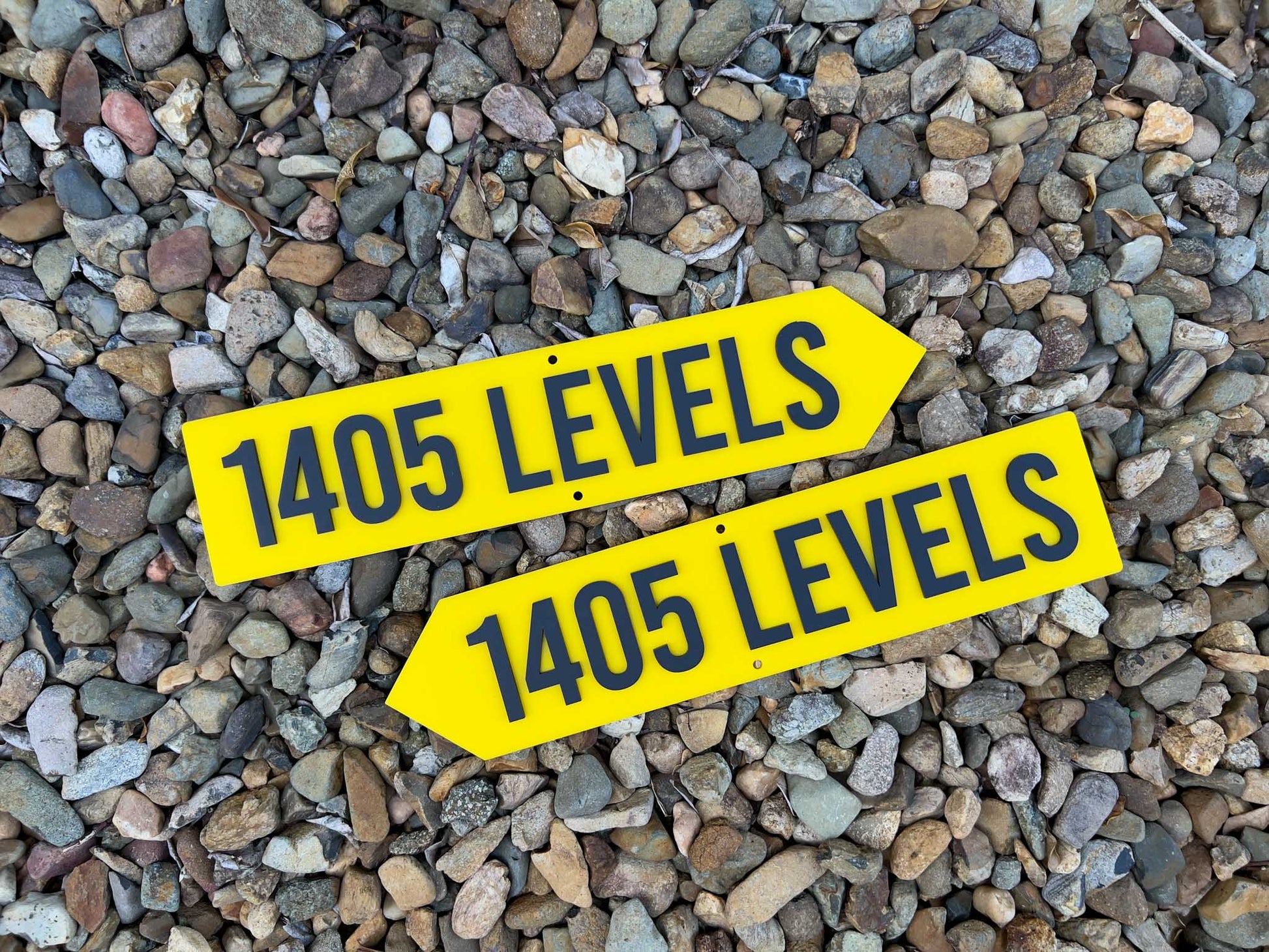 Two yellow signs with '1405 LEVELS' text on a gravel background | Coji Designs