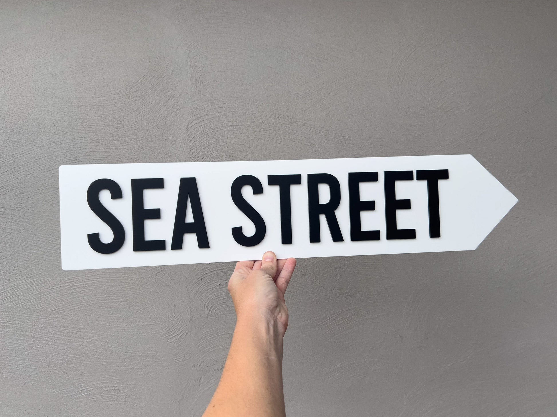 Hand holding a 'Sea Street' sign against a gray background | Coji Designs