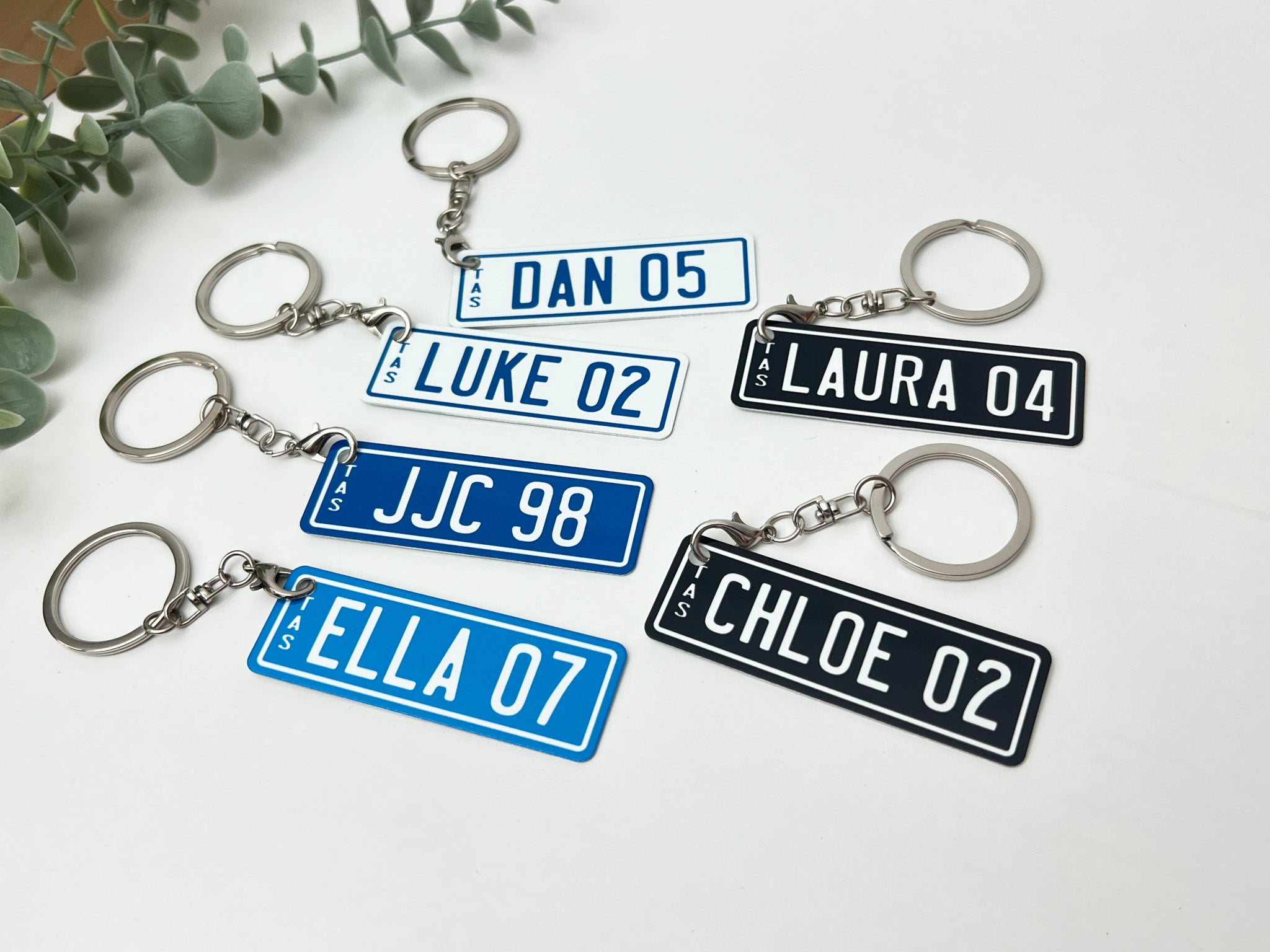 Custom number plate accessory keychains with TAS on the left hand side and custom large text.