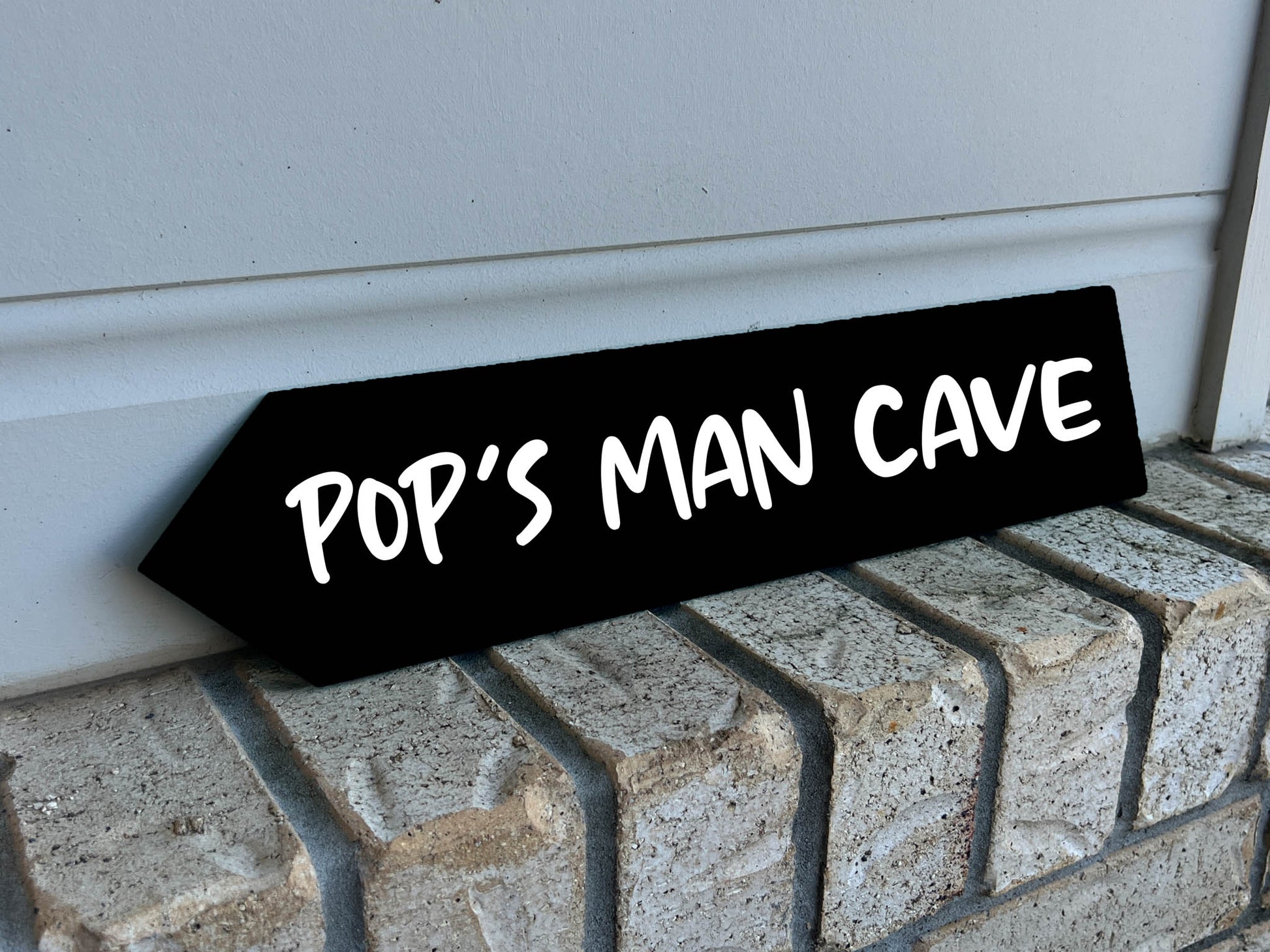 Black sign with 'Pop's Man Cave' text on a brick step | Coji Designs