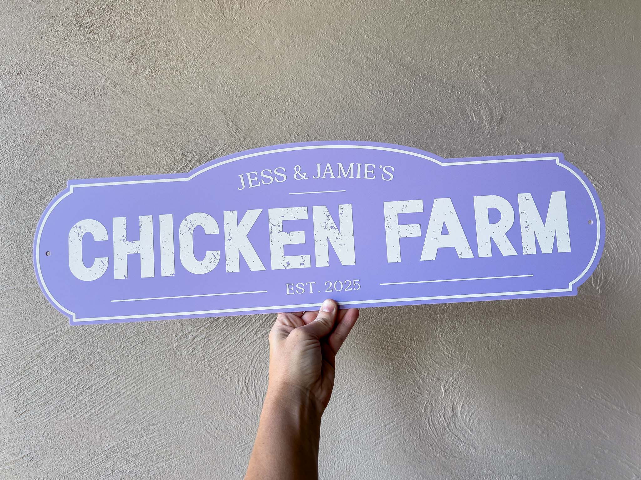 A retro vintage style sign in a light purple colour with white text that says 'Jess & Jamie's Chicken Farm Est. 2025'.
