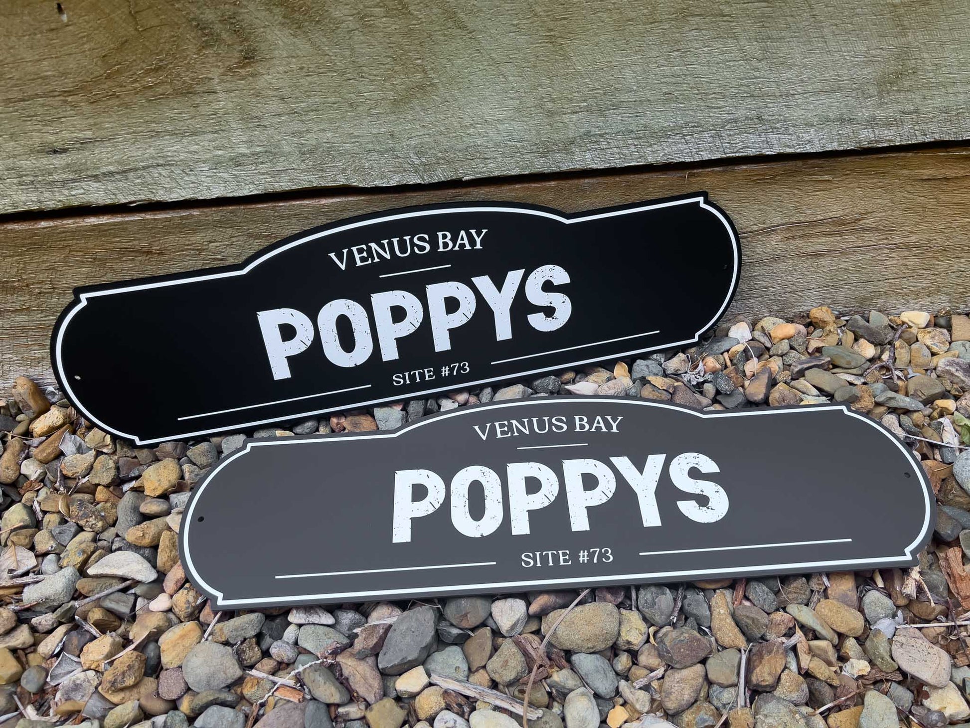 Two farmstead style signs that say 'Poppys' in grey, black and white text.