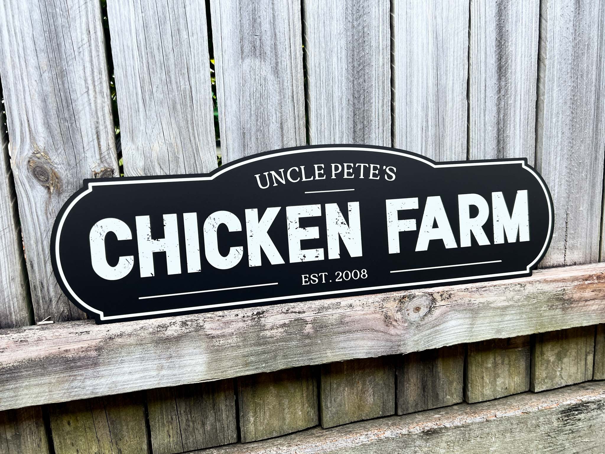 Vintage style black sign with white weathered text that reads 'Chicken Farm Est. 2008'.